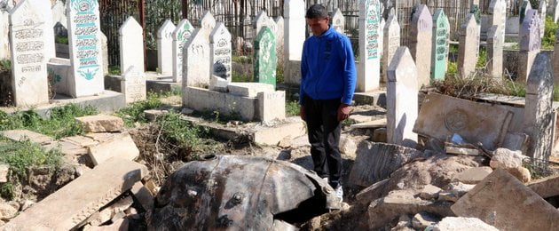 210069_man_looks_down_at_an_unexploded_barrel_bomb_dropped_by_forces_loyal_to_syria_s_president_assad_at_a_cemetery_in_al-qatanah_neighbourhood_of_aleppo